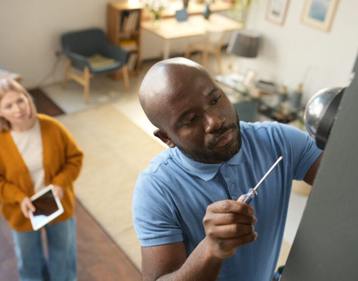 High angle view at adult African American man doing home repairs and setting up doorbell or camera copy space